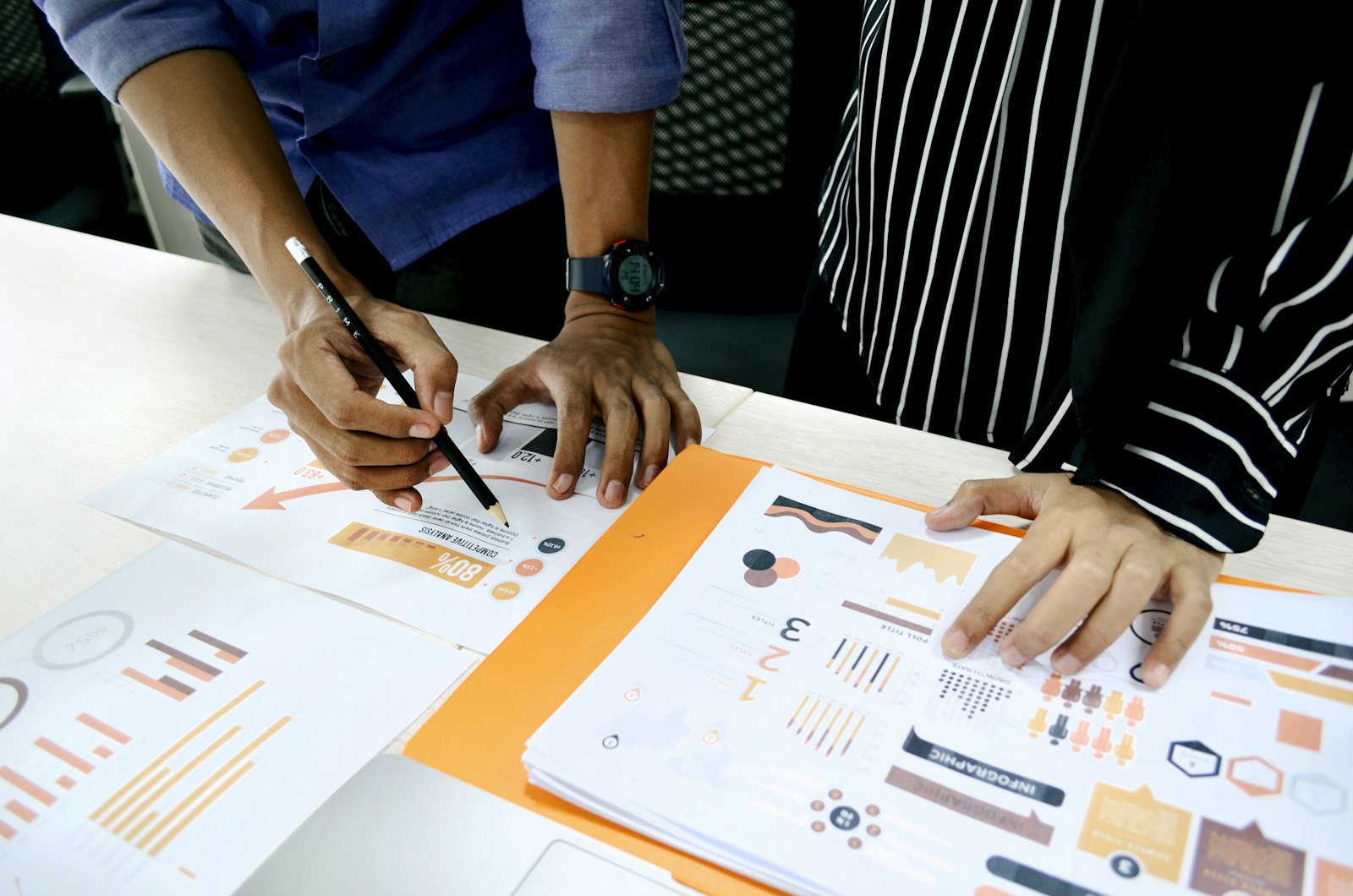 Two people review printed research charts together, writing and pointing to the findings.